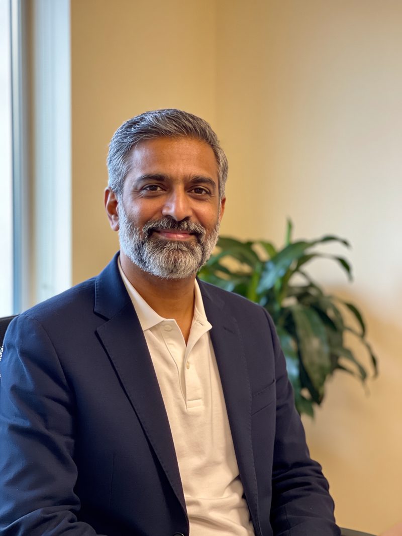 Portrait of Arjun Menon, a partner, in a bright office